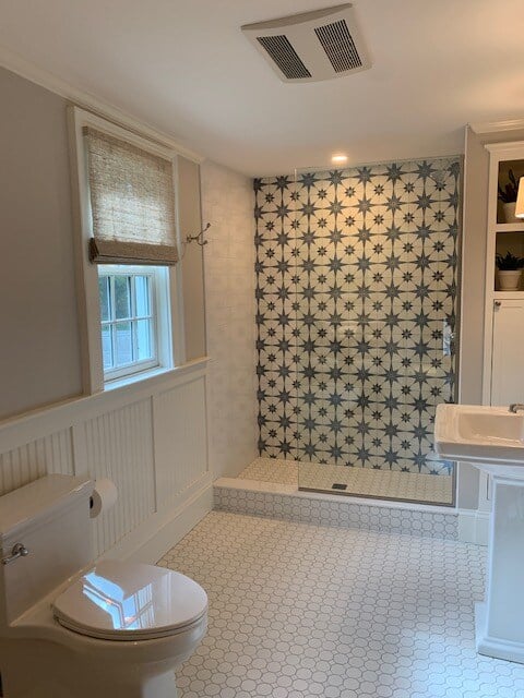 Bathroom with a patterned tile shower and hexagonal floor tiles, remodeled by Oxland Builders in New Hampshire