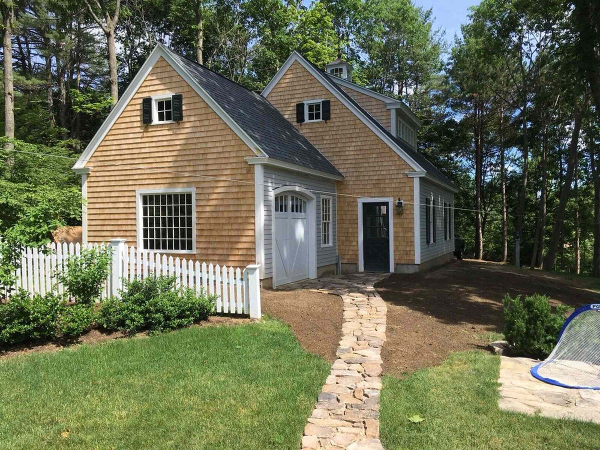 Garage with cedar shake siding and a white picket fence, designed by Oxland Builders in New Hampshire