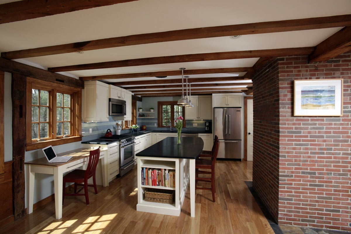 Rustic kitchen with exposed wood beams and brick accents, remodeled by Oxland Builders in New Hampshire